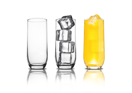 Glass of orange soda with ice cubes empty glass and bubbles with reflection on white backgroundの写真素材