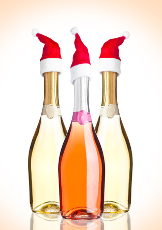 Bottles of pink yellow champagne with santa hat on pink backgroundの写真素材