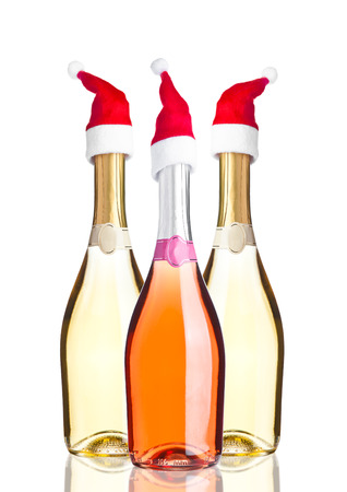 Bottles of pink yellow champagne with santa hat on white backgroundの写真素材