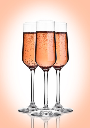 Glass of pink rose champagne with bubbles on pink backgroundの写真素材