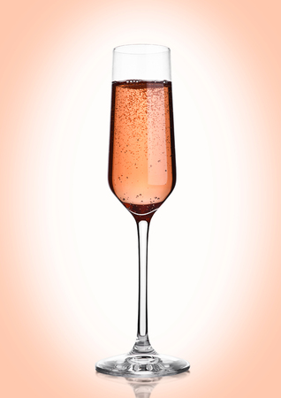 Glass of pink rose champagne with bubbles on pink backgroundの写真素材