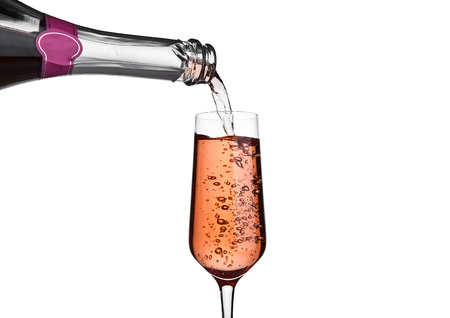 Pouring pink rose champagne from bottle to glass on white backgroundの写真素材