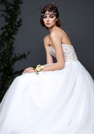 Young bride woman in wedding dress on grey background in the studio with make up and hairstyleの写真素材