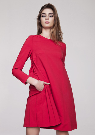 Beautiful young girl in red dress fashion on grey backgroundの写真素材