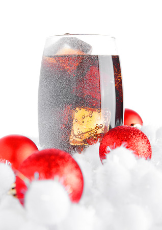 Glass of cola soda  on snow and christmas balls on white backgroundの写真素材
