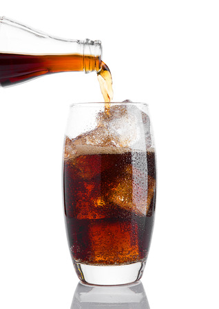 Pouring cola soda drink into the glass with ice on white backgroundの写真素材