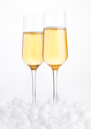Glasses of champagne with bubbles on snow on white backgroundの写真素材