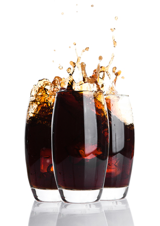 Glasses of cola with splash and ice cubes on white backgroundの写真素材
