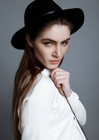 Beautiful fashion model in white with black hat in studioの写真素材