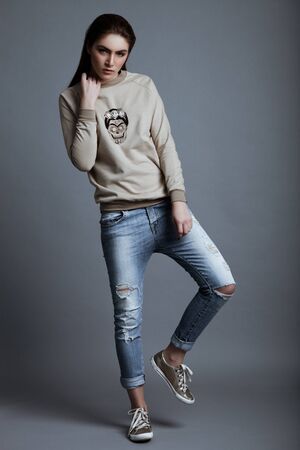 Beautiful fashion model wearing grey jumper skull in studio