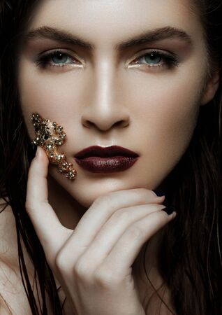 Beautiful girl holding golden diamond frog jewelry on green plants backgroundの写真素材