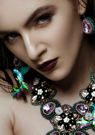 Beautiful woman wearing exotic tropical jewelry on green plants backgroundの写真素材
