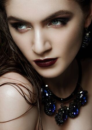 Beautiful woman wearing exotic tropical jewelry on green plants backgroundの写真素材