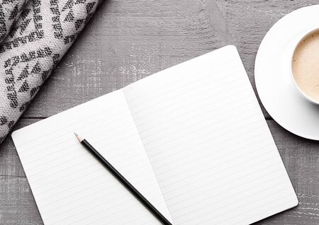 Cup of cappuccino with grey wool scarf and diary book on wooden backgroundの写真素材