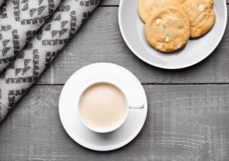 Cup of cappuccino with grey wool scarf and cookies on wooden backgroundの写真素材