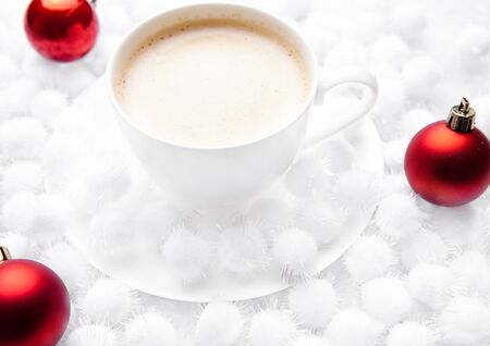 Cup of cappuccino coffee on snow christmas balls on snow backgroundの写真素材