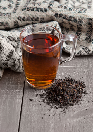 Cup of black healthy tea scarf and loose tea on wooden backgroundの写真素材