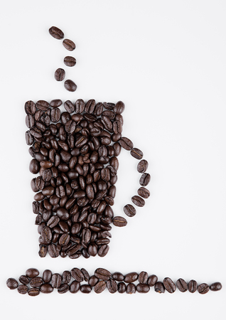 Cup of black coffee shape created from beans on white backgroundの写真素材