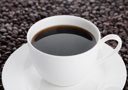 Cup of black  coffee for breakfast with beans on coffee beans backgroundの写真素材