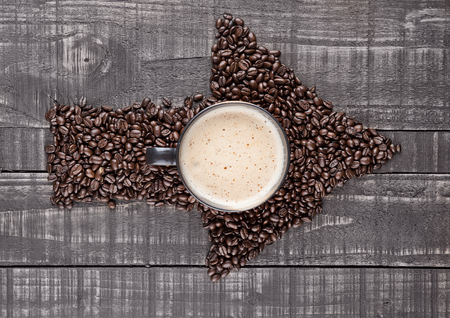 Large cup with hot cappuccino with coffee beans on wooden boardの写真素材