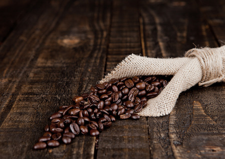 Coffee beans in linen cloth on wooden boardの写真素材