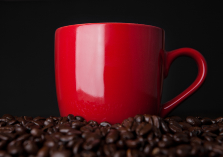 Hot red coffee cup on beans for breakfast morning on wooden boardの写真素材