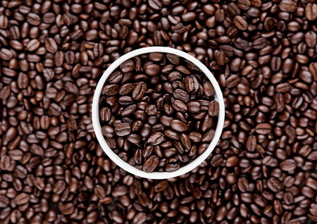 Hot coffee cup on beans for breakfast morning on wooden boardの写真素材
