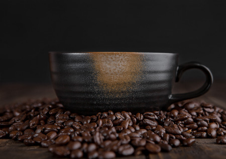 Large cup with hot cappuccino with coffee beans on wooden boardの写真素材