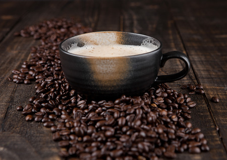 Large cup with hot cappuccino with coffee beans on wooden boardの写真素材