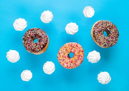 Chocolate and pink donuts with meringues  for breakfast on blue backgroundの写真素材
