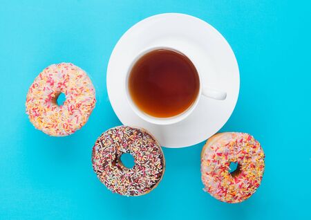 Cup of tea for breakfast with donuts in motion on blue  backgroundの写真素材