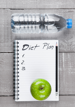 Writing pad with apples and water as diet  idea on wooden boardの写真素材