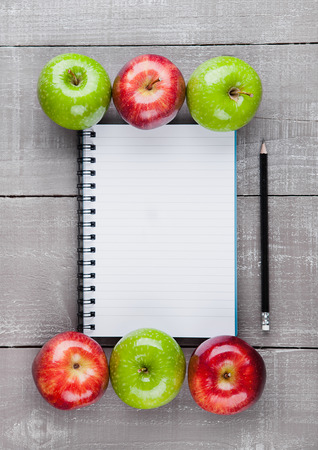 Writing pad with healthy apples as diet plan idea on wooden boardの写真素材