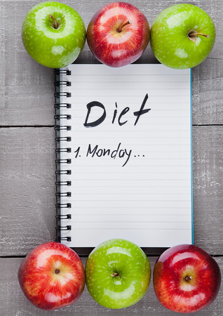 Writing pad with healthy apples as diet plan idea on wooden boardの写真素材