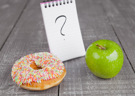 Donut and apple healthy food choices  on wooden board backgroundの写真素材