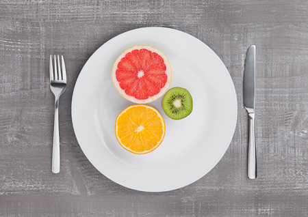 Fruits mix grapefruit orange and kiwi on the plate on wooden backgroundの写真素材