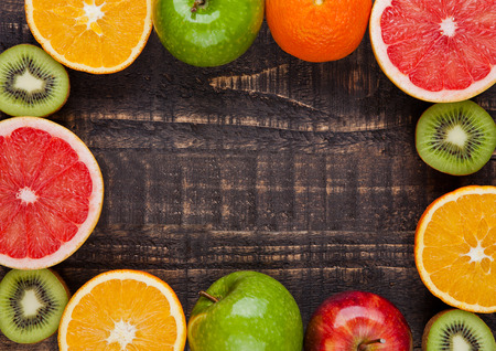 Fruits mix grapefruit orange apples kiwi on wooden backgroundの写真素材