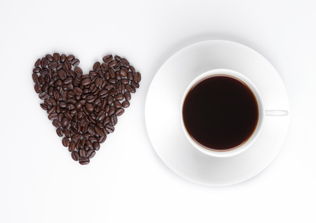 Cup of hot coffee with beans heart shape on white backgroundの写真素材