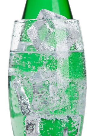 Bottle and glass with healthy sparkling  water with ice cubes on whiteの写真素材
