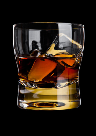 Glass of whiskey with golden ice cubes isolated on black backgroundの写真素材
