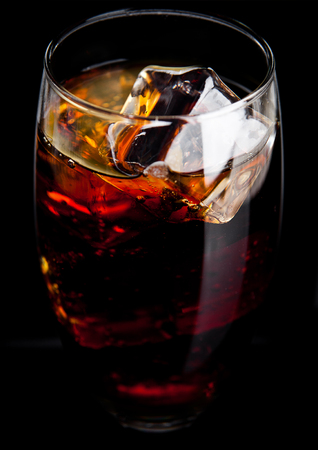 Glass of cold cola soda drink with ice cubes on black backgroundの写真素材