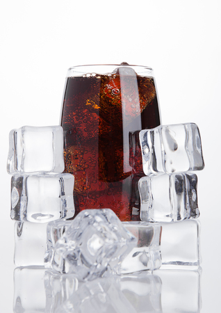 Glass of cold cola soda drink with ice cubes on white backgroundの写真素材