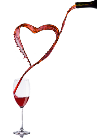 Pouring wine heart romantic shape to elegant glass on white backgroundの写真素材
