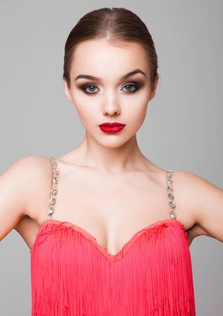 Beautiful ballroom dancer girl portrait red dress on grey backgroundの写真素材
