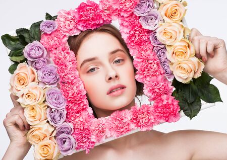 Happy cute girl holding frame made from red,purple and yellow roses mix on white backgroundの写真素材