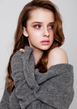 Young beautiful fashion model wearing knitwear jumper on grey backgroundの写真素材