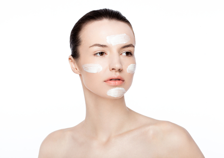 Beautiful woman girl with face cream natural makeup portrait on white backgroundの写真素材