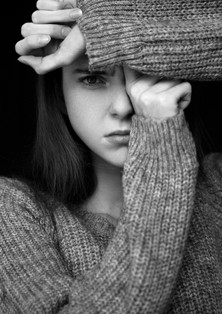 Model portrait test with young beautiful fashion model wearing grey jumper on black background.Dramatic portrait.の写真素材