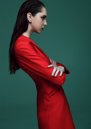 Fashion model with wet hair wearing red long coat on green background. Fashion portrait.の写真素材