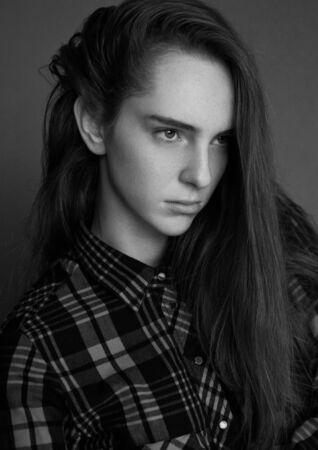 Model portrait test with young beautiful fashion model with long hair wearing white shirt on grey backgroundの写真素材